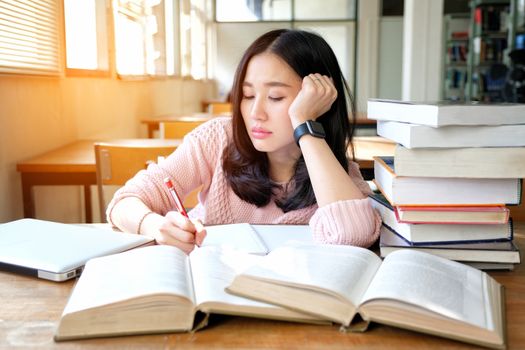 Young woman studying in a library and thinking of something