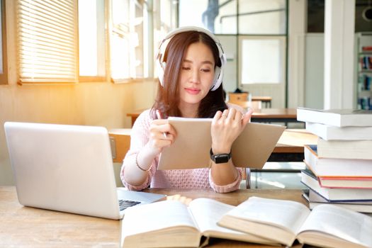 Young woman in a good mood listening to music  while studying in a library