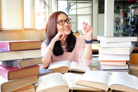 Young woman thinking while studying in library