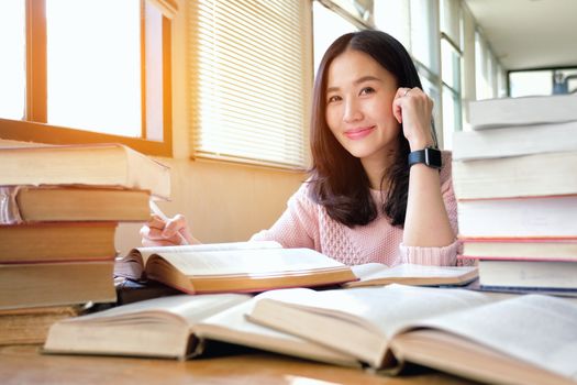 Young woman taking note and studying in library