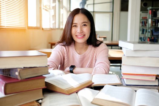 Young woman taking note and studying in library