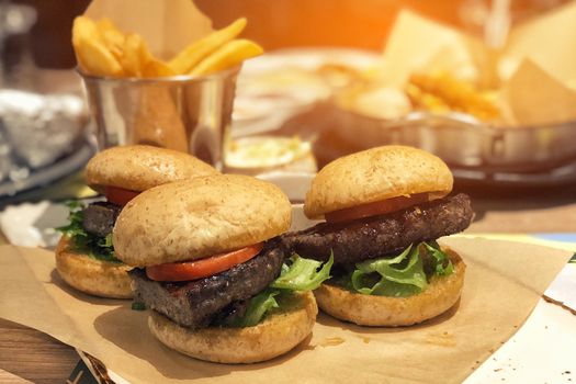 Fresh tasty meat burger and french fries on wooden table