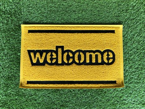 Yellow welcome word of green foot scraper.Microfiber fabric texture background.