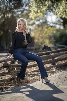 A gorgeous blonde model poses outdoors in her fall clothes