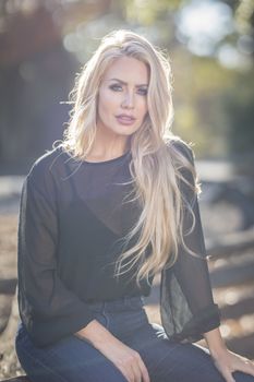 A gorgeous blonde model poses outdoors in her fall clothes