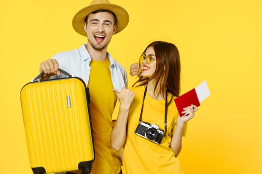 Happy man with a suitcase and women with a camera go on a trip and passport tickets
