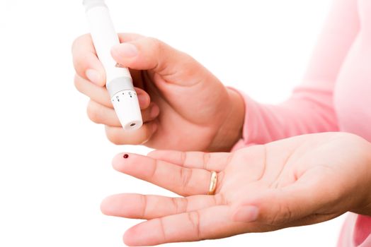 Closeup woman measuring glucose level using a hand test lancelet on the finger she monitors high blood sugar diabetes and glycemic health care concept