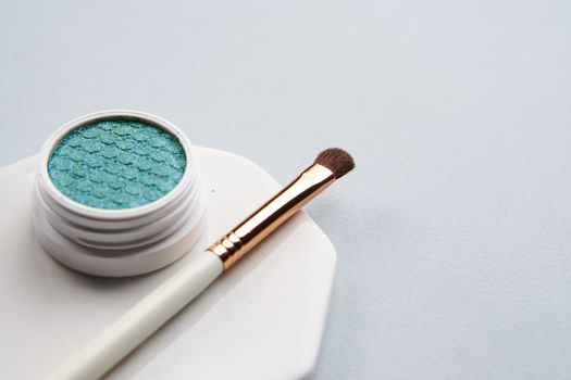 Green eyeshadow and makeup brush on white stand isolated background. High quality photo