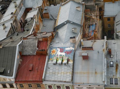 Top view of old roofs of houses with graffiti in the form of a horse in the clouds. Lviv