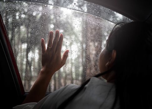 Sad young woman sitting lonely thinking about her lover in the car on a rainy day.