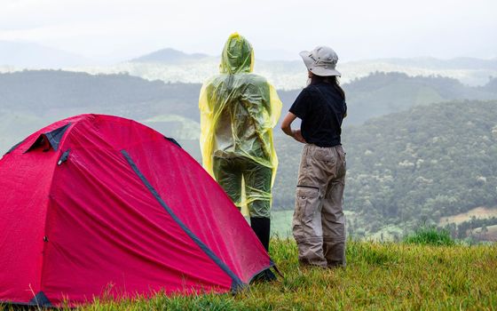 Couple stand at tent and enjoying the beautiful foggy mornig on the mountain top. Doi Mae Tho, Chiang Mai, Thailand.