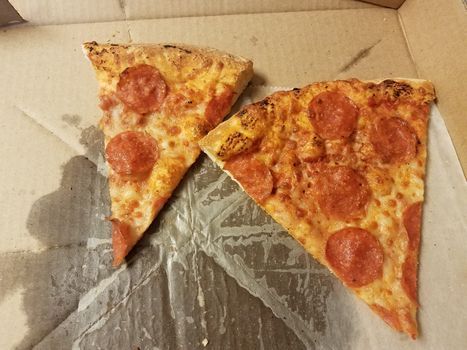 pepperoni and cheese pizza slices with grease in cardboard box