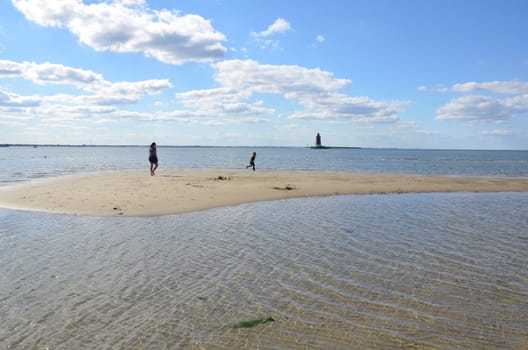 mother and child playing on beach with water and lighthouse