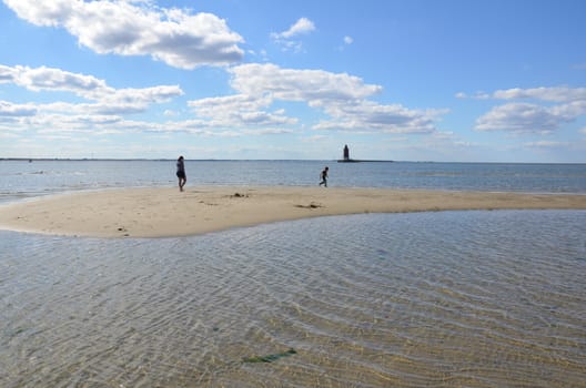 mother and child playing on beach with water and lighthouse