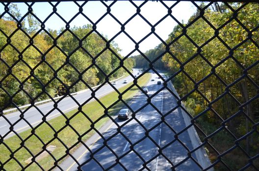 metal chain link fence over highway or road with cars