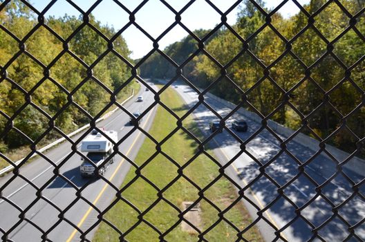 metal chain link fence over highway or road with cars