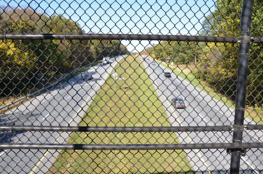 metal chain link fence over highway or road with cars