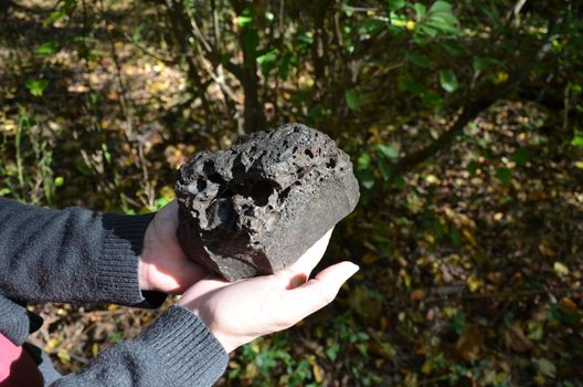woman hand holding black coal or slag rock or stone
