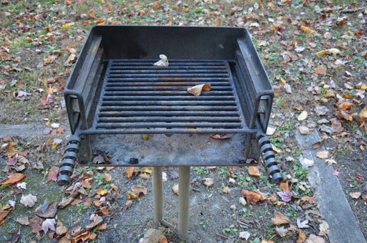 dirty metal barbecue grill outdoor at park with leaves