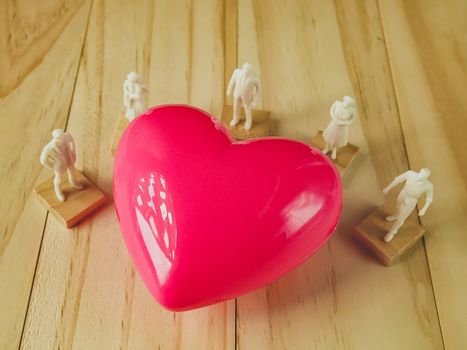 The pink heart and white figure on wood table for Health, medical content.