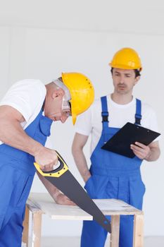 Business, building, teamwork and people concept - group of builders in hardhats with tools indoors
