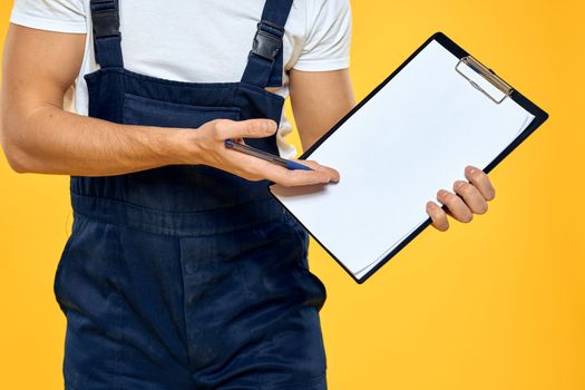 Man in working uniform documents rendering of services delivery service yellow background. High quality photo