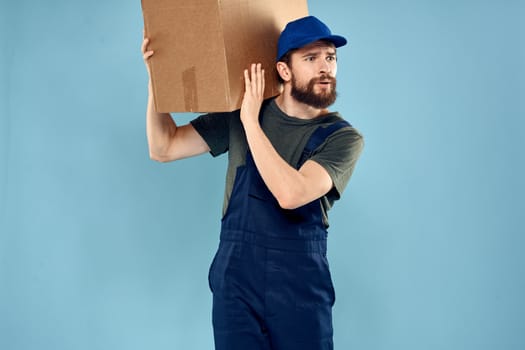 A man in working uniform with boxes in the hands of a carriage delivery service blue background. High quality photo