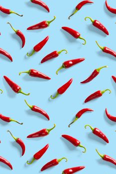Creative background made of red chili or chilli on blue backdrop. Minimal food backgroud. Red hot chilli peppers background, not pattern