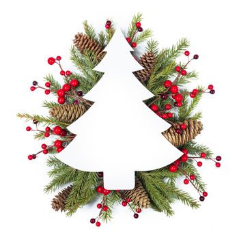 Christmas white fir tree shaped blank card with copy space and decor of fir tree branch bauble cones red holly berry isolated on white background