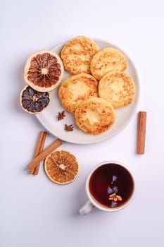 Cottage cheese fritters with hot black aromatic tea, Christmas breakfast mood with anise and cinnamon on white background, top view