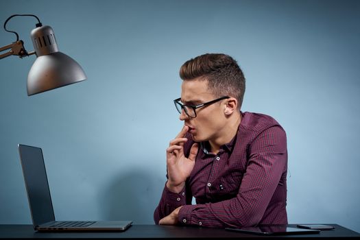 A man in a shirt with a laptop at the table is a manager in the office and a lamp cabinet model. High quality photo