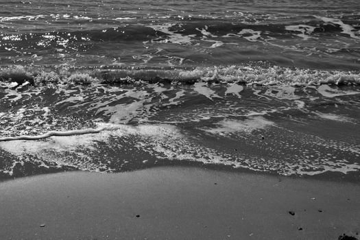 Waves, light and sand texture on the beach in the morning