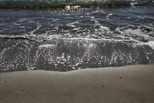 Waves, light and sand texture on the beach in the morning