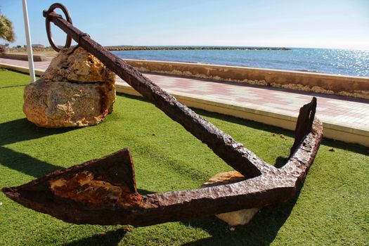 Santa Pola, Spain- February 16, 2018: Old anchor on a promenade of Santa Pola, Alicante. Mediterranean sea on background.