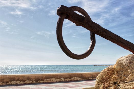 Santa Pola, Spain- February 16, 2018: Old anchor on a promenade of Santa Pola, Alicante. Mediterranean sea on background.