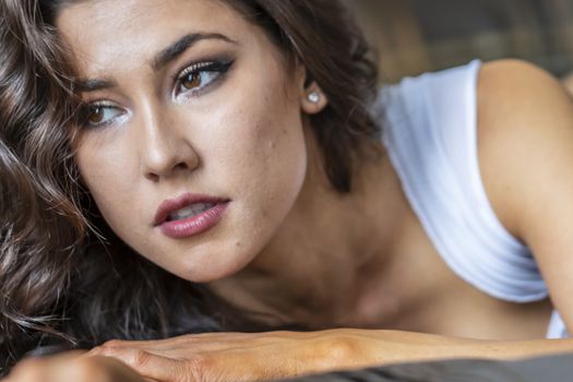 A gorgeous brunette model poses in lingerie in a bedroom environment