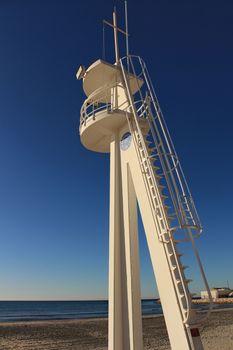 Santa Pola, Spain- February 16, 2018: Lifeguard tower on a quiet and lonely beach in a sunny day in southern Spain, Alicante. Palm trees in the background.