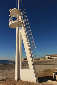 Santa Pola, Spain- February 16, 2018: Lifeguard tower on a quiet and lonely beach in a sunny day in southern Spain, Alicante. Palm trees in the background.