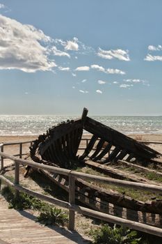 Old abandoned boat on the beach in Santa Pola. Salinas in the background under blue sky