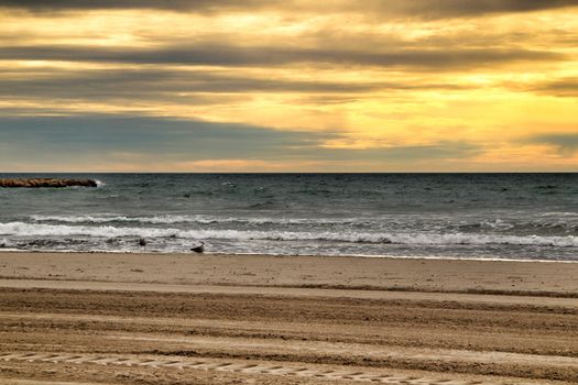 Beach under golden stormy sky in Santa Pola, Alicante, Spain