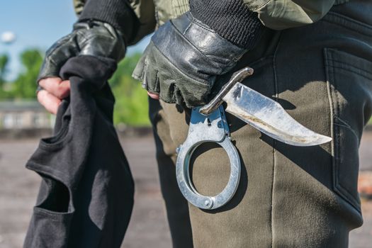 Standard military and law enforcement equipment, handcuffs and balaclava in hands