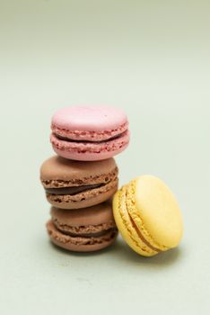 Pile of colored tasty macaroons over a green background.