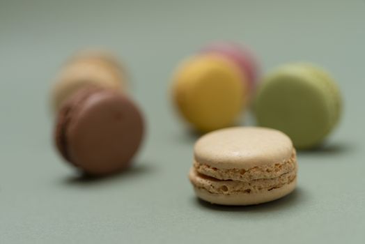 Assorted colored tasty macaroons over a green background.