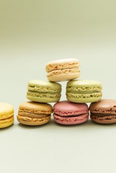 Pile of colored tasty macaroons over a green background.