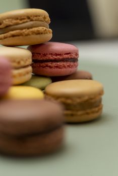 Pile of colored tasty macaroons over a green background.