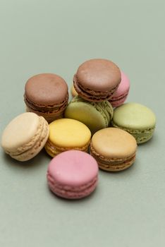 Assorted colored tasty macaroons over a green background.