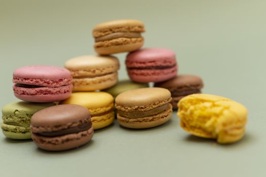 Pile of colored tasty macaroons over a green background.