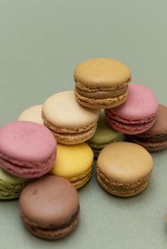 Assorted colored tasty macaroons over a green background.
