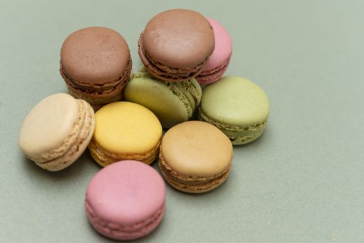 Assorted colored tasty macaroons over a green background.