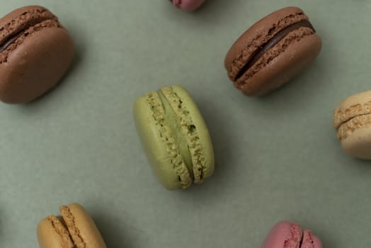 Assorted colored tasty macaroons over a green background.